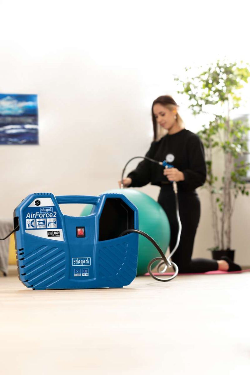 Mobiler Kompressor Air Force2 von Scheppach, 220-240V 50Hz 1100W, mit Schlauch und Aufblasnadel, eine Person bläst einen Gymnastikball auf.