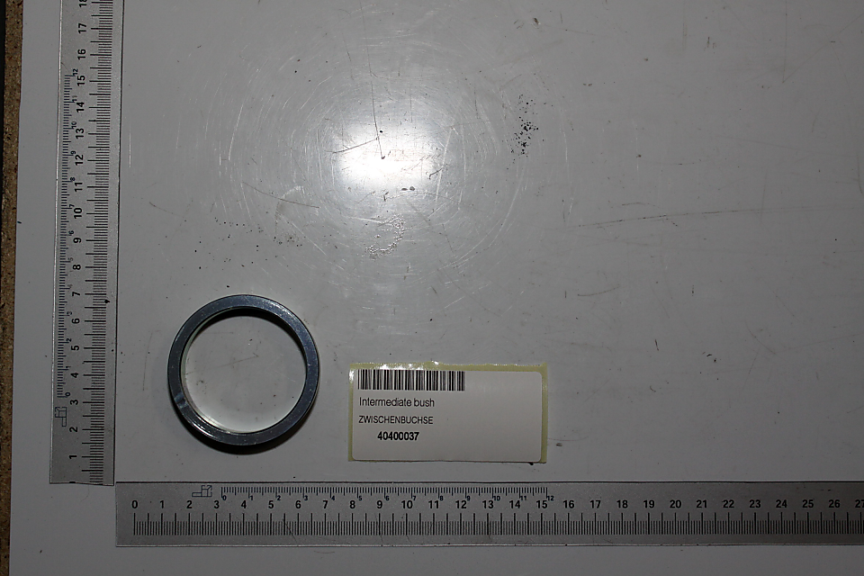 Zwischenbuchse mit der Artikelnummer 40400037. Die Buchse liegt auf einer weißen Fläche neben einem Maßstab. Die Buchse wird von oben fotografiert.