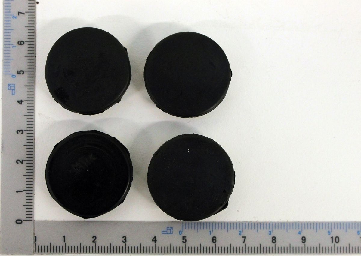 Ein Satz von vier schwarzen Stopfen für Seitenteile, jeweils mit einem Durchmesser von etwa 5 cm, wie auf einem Lineal gemessen.
