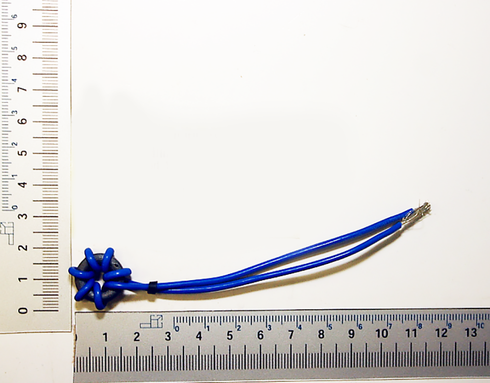 Ein Endstörfilter von Scheppach neben einem Lineal zur Größenveranschaulichung. Der Filter ist etwa 10 cm lang.