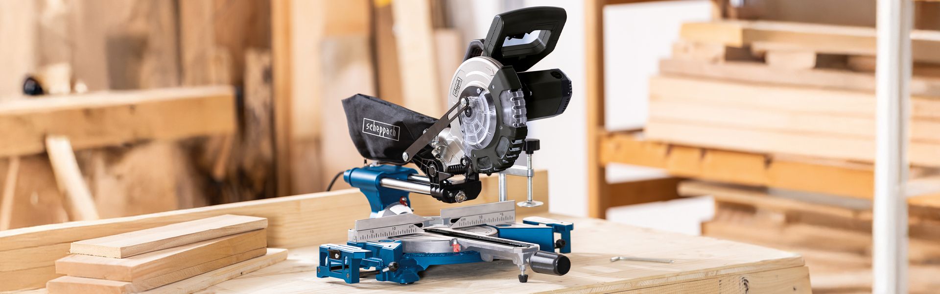 Scheppach circular saw on a wooden board with additional wooden pieces in the background. Tool in a workshop setting.