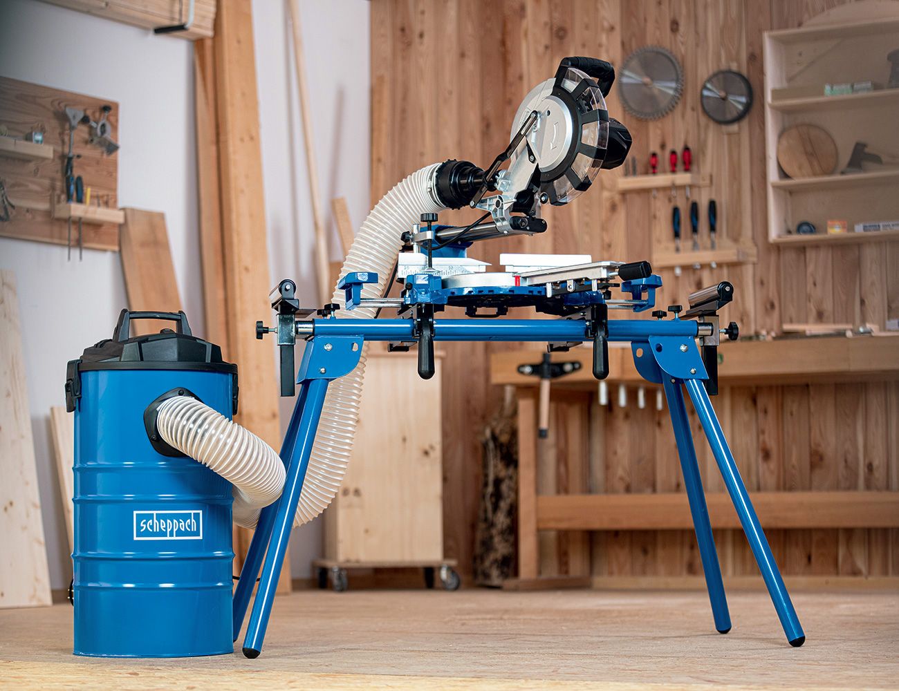 Scheppach mitre saw with stand. The saw is mounted on a blue stand and connected to a dust extractor.
