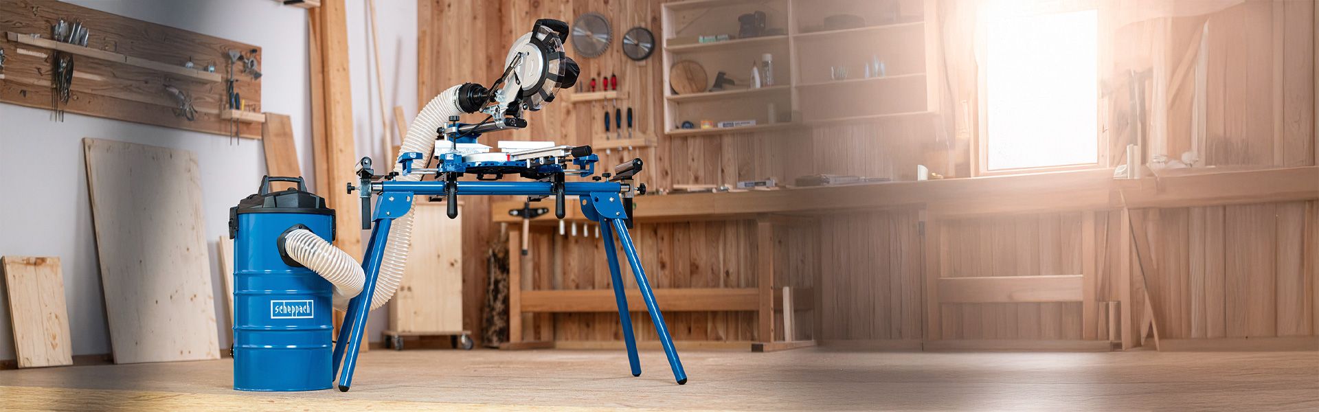 Scheppach mitre saw with accessories in a workshop. Wooden shelves and tools in the background.