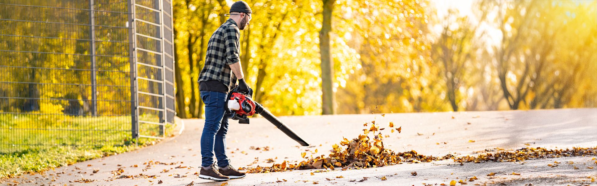 A man using a leaf blower in an autumn garden. Scheppach tools for the gardening season.