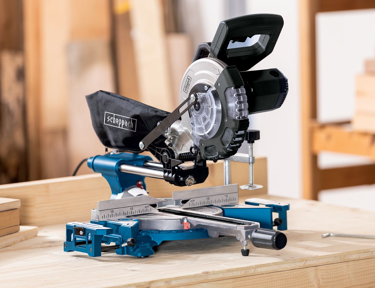 Scheppach circular saw on a wooden table. The saw table has a measuring scale and a clamp for wooden pieces.